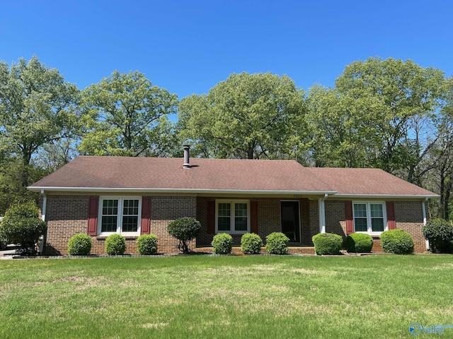 single story home featuring brick siding, a shingled roof, and a front yard