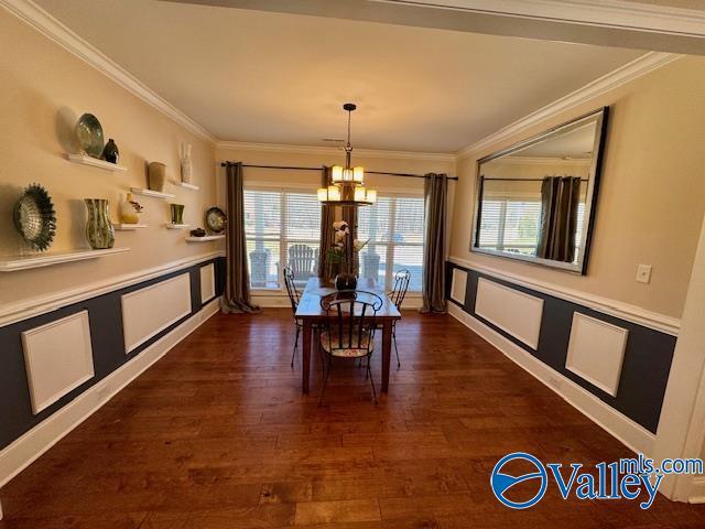 dining room featuring dark wood-type flooring, ornamental molding, and an inviting chandelier