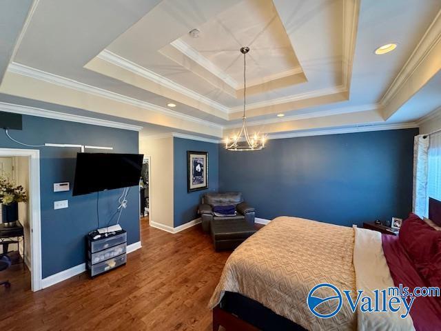 bedroom featuring crown molding, dark hardwood / wood-style floors, a raised ceiling, and a chandelier