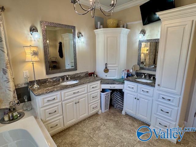 bathroom with a notable chandelier, crown molding, a tub, and vanity