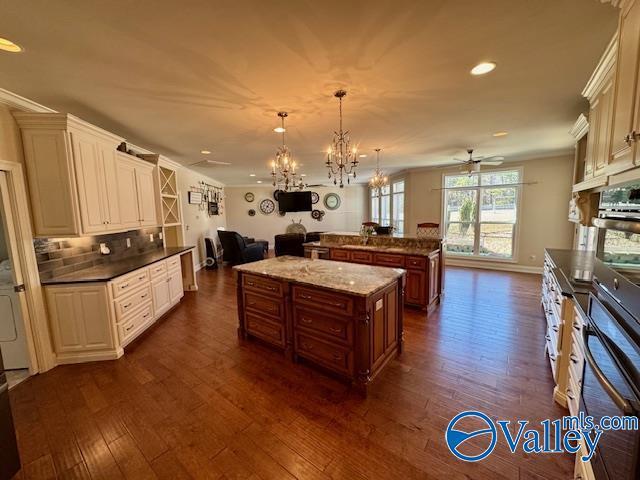 kitchen featuring a center island, hanging light fixtures, dark hardwood / wood-style flooring, ceiling fan with notable chandelier, and decorative backsplash