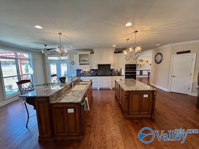 kitchen with a spacious island, a breakfast bar, sink, decorative light fixtures, and a chandelier