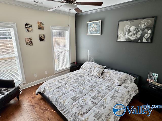 bedroom with crown molding, dark hardwood / wood-style floors, and ceiling fan