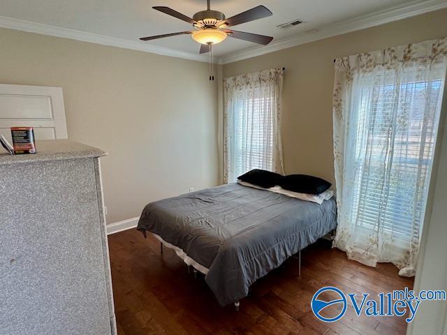 bedroom with ornamental molding, dark hardwood / wood-style floors, and ceiling fan