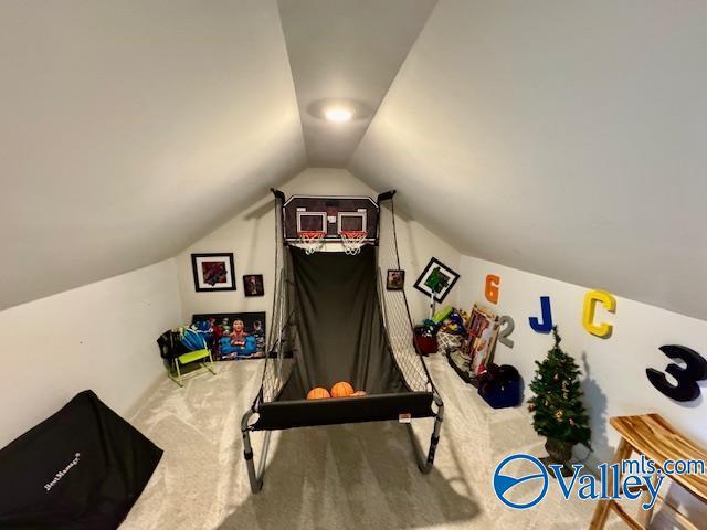 exercise room with vaulted ceiling and carpet flooring