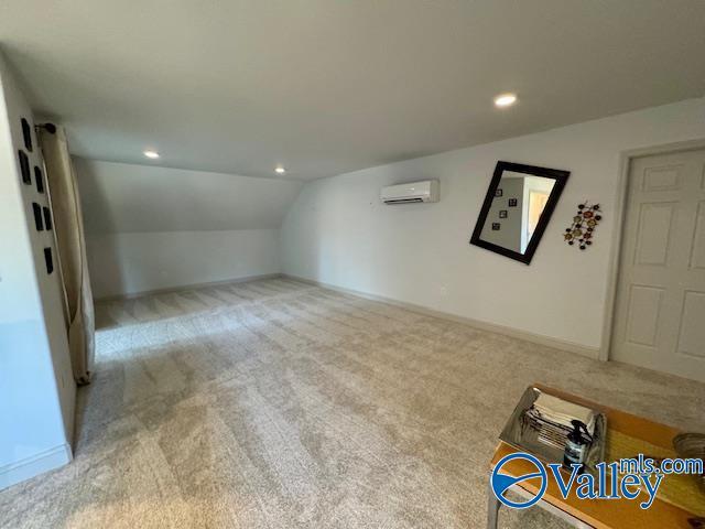 interior space with light carpet, lofted ceiling, and an AC wall unit