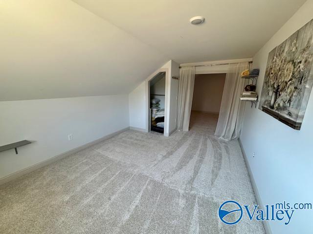 bonus room featuring lofted ceiling and light carpet