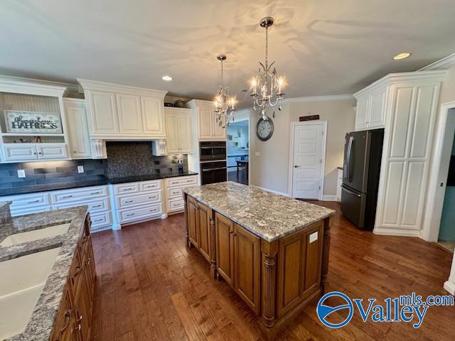 kitchen with stainless steel refrigerator, decorative light fixtures, a center island, and white cabinets