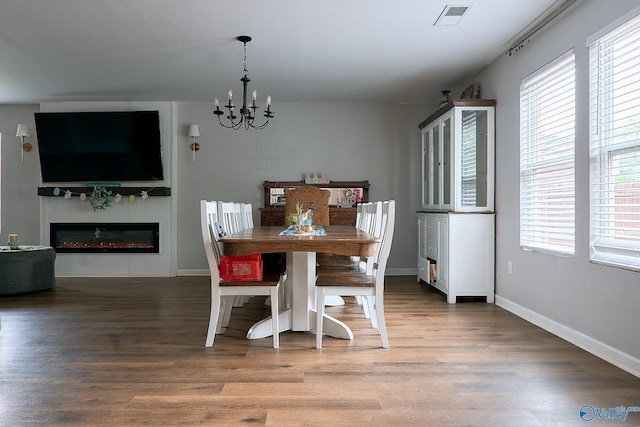 dining area featuring a chandelier, visible vents, a healthy amount of sunlight, and wood finished floors