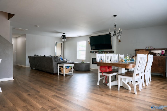 dining room with baseboards, wood finished floors, and ceiling fan with notable chandelier