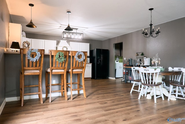 dining space with an inviting chandelier, washer / dryer, and wood finished floors