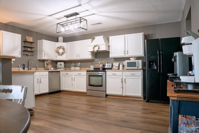 kitchen featuring stainless steel appliances, visible vents, white cabinetry, and custom range hood