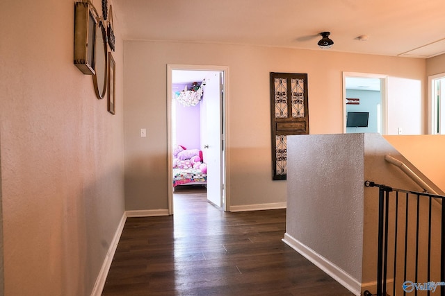 corridor featuring baseboards and dark wood-type flooring