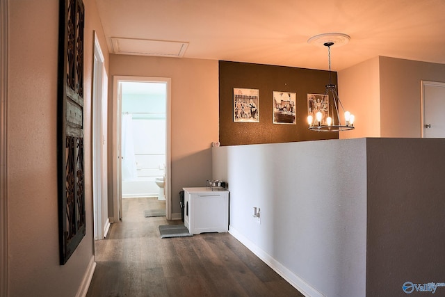 corridor with an inviting chandelier, baseboards, and dark wood-type flooring