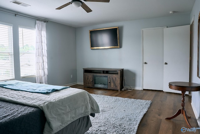 bedroom with baseboards, ceiling fan, wood finished floors, and visible vents