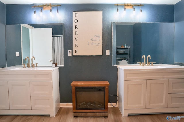 bathroom with a sink, wood finished floors, and two vanities