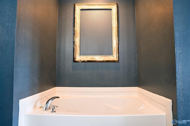 bathroom with a garden tub and a textured wall