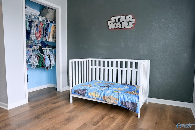 bedroom featuring baseboards, wood finished floors, and a closet