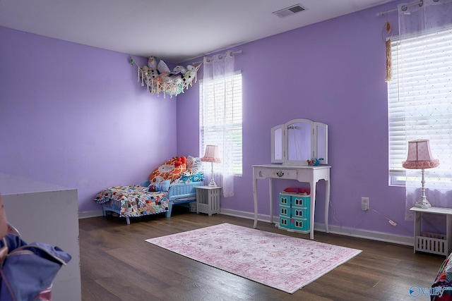 bedroom with visible vents, baseboards, and wood finished floors