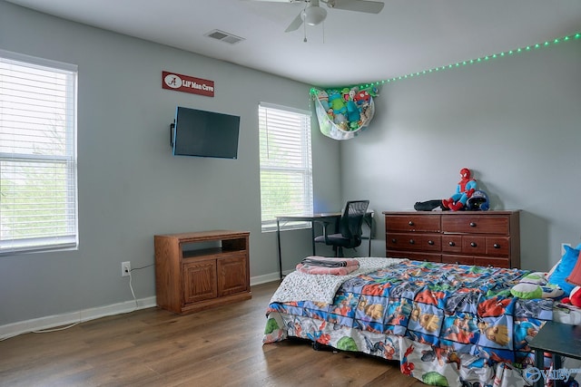bedroom with a ceiling fan, baseboards, visible vents, and wood finished floors