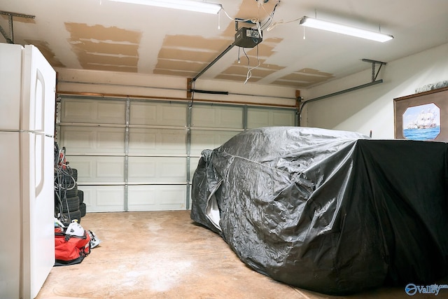 garage featuring freestanding refrigerator and a garage door opener