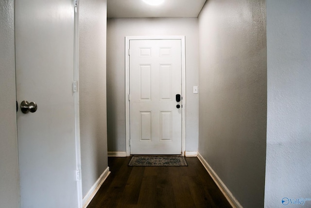 doorway featuring baseboards and dark wood-type flooring