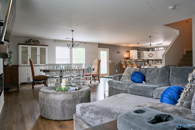 living area featuring stairs, a chandelier, and dark wood-style floors