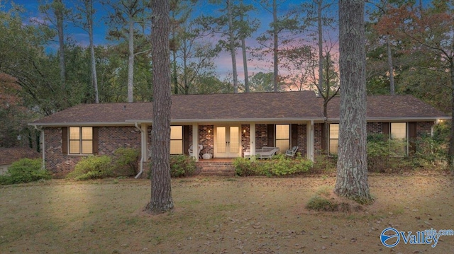 ranch-style home featuring a porch and a yard