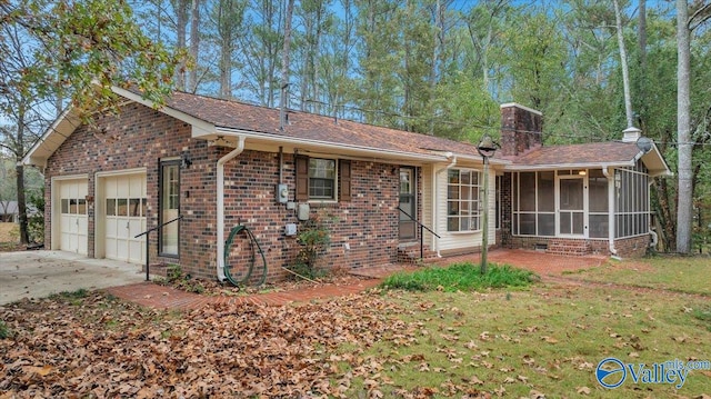 rear view of house with a lawn, a garage, and a sunroom