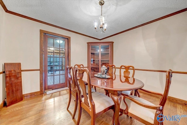 dining area featuring a textured ceiling, light hardwood / wood-style flooring, crown molding, and a notable chandelier