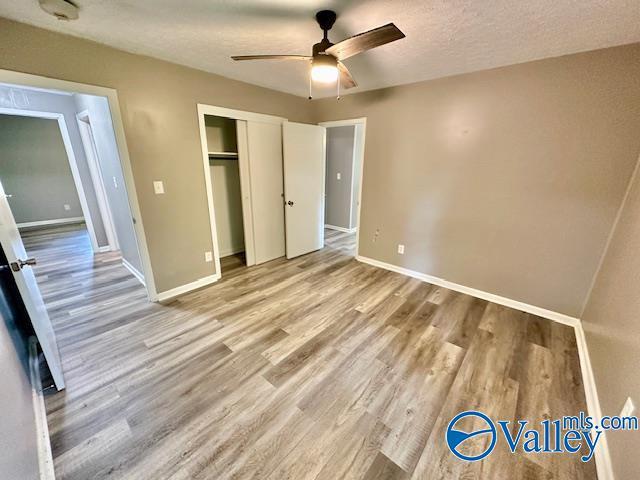196 Johnson St, Rainsville, AL 35986 - unfurnished bedroom with wood finished floors, baseboards, a closet, and a ceiling fan