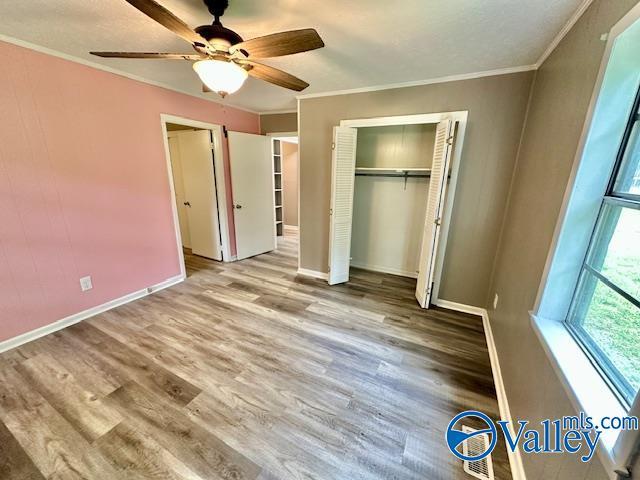196 Johnson St, Rainsville, AL 35986 - unfurnished bedroom with wood finished floors, baseboards, a closet, crown molding, and a ceiling fan