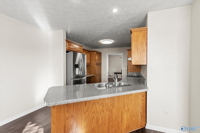 kitchen featuring kitchen peninsula, dark wood-type flooring, a textured ceiling, stainless steel fridge with ice dispenser, and sink