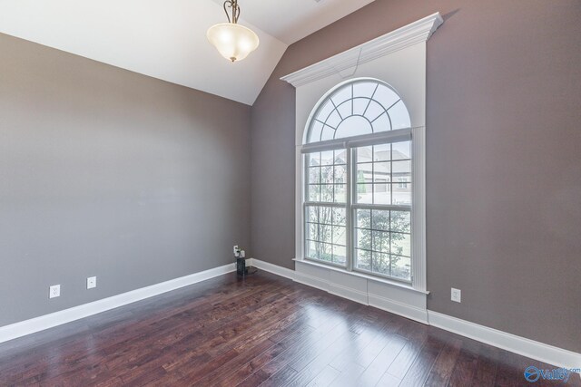 spare room with dark wood-type flooring and vaulted ceiling