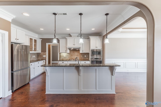 kitchen with white cabinets, a kitchen island with sink, stainless steel appliances, and dark wood-type flooring