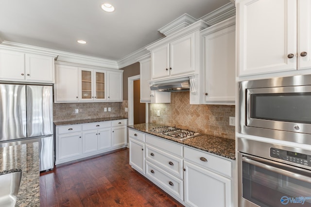 kitchen with dark wood-type flooring, appliances with stainless steel finishes, white cabinets, and dark stone counters