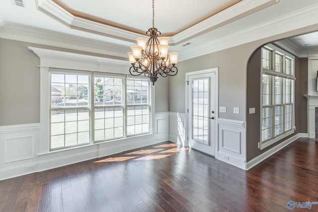 unfurnished dining area featuring a raised ceiling, ornamental molding, and dark hardwood / wood-style flooring