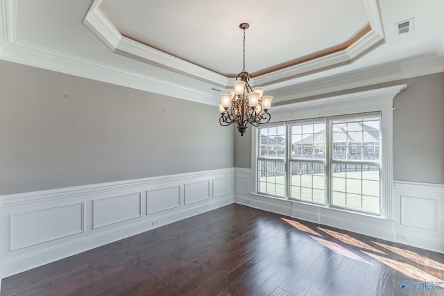 empty room featuring a notable chandelier, ornamental molding, a tray ceiling, and dark hardwood / wood-style floors