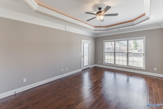 empty room featuring ornamental molding, dark hardwood / wood-style floors, a tray ceiling, and ceiling fan