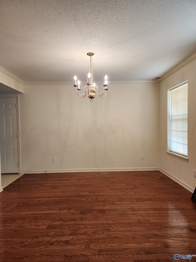 empty room featuring dark hardwood / wood-style flooring, ornamental molding, a textured ceiling, and a chandelier