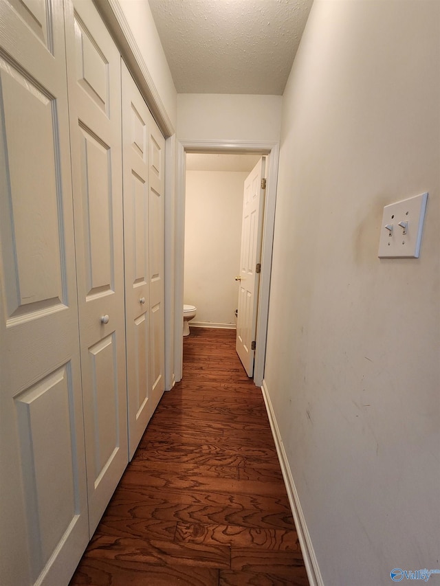 hallway featuring dark hardwood / wood-style floors and a textured ceiling