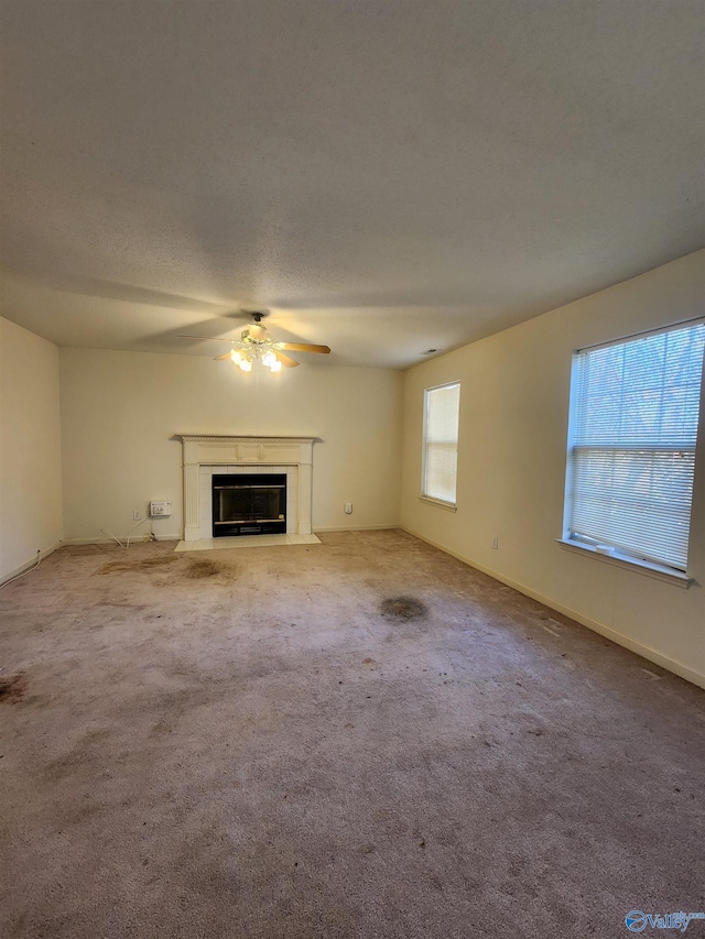 unfurnished living room with light carpet, ceiling fan, and a textured ceiling