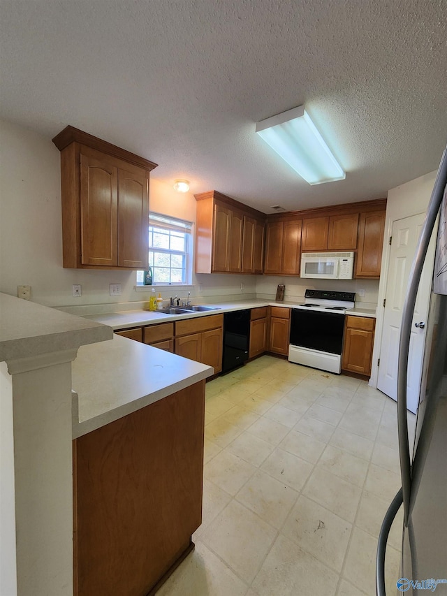 kitchen featuring kitchen peninsula, sink, white appliances, and a textured ceiling