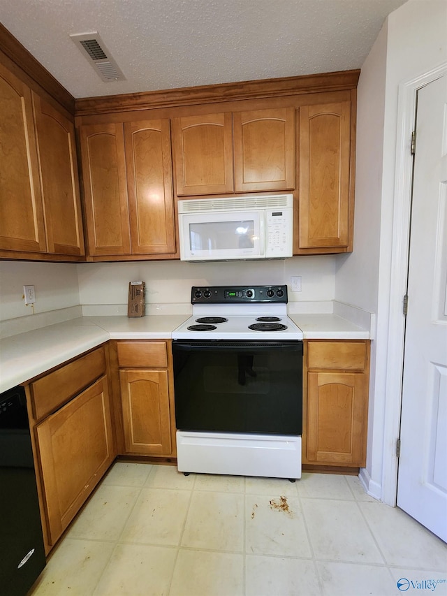 kitchen with a textured ceiling, white appliances, and light tile patterned flooring