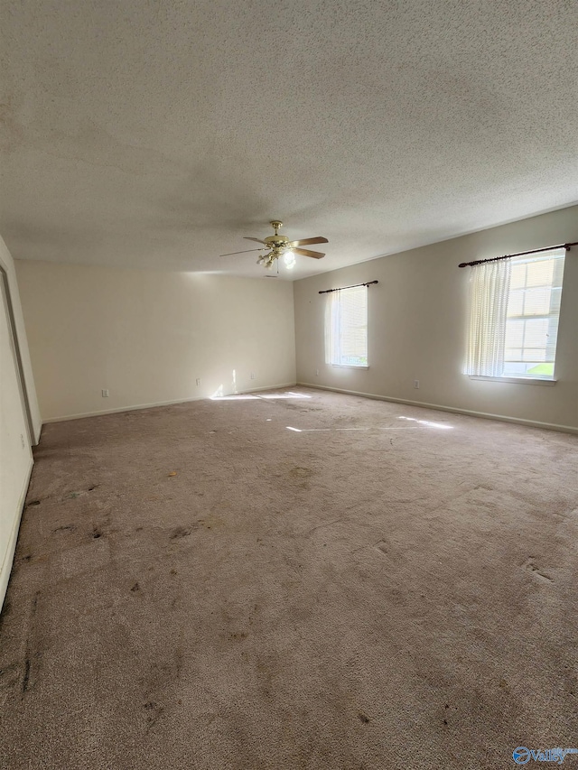 carpeted spare room featuring ceiling fan and a textured ceiling