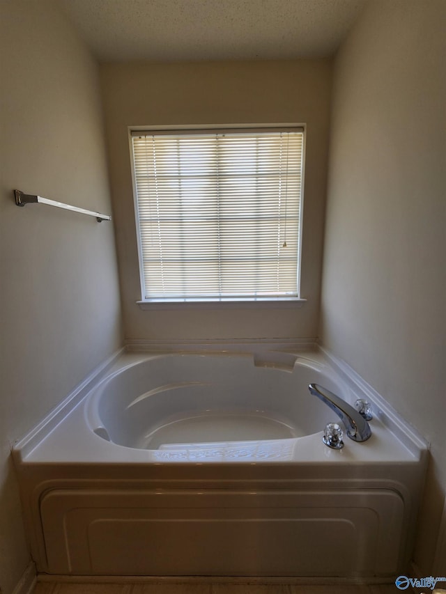 bathroom featuring a textured ceiling and a tub to relax in