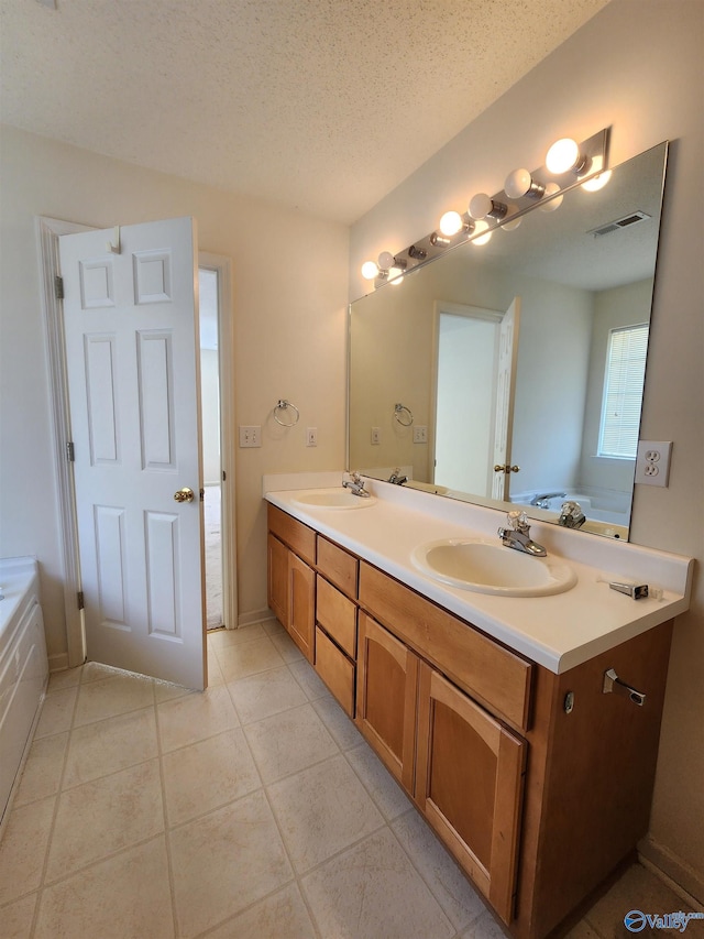 bathroom with tile patterned floors, a bathtub, vanity, and a textured ceiling