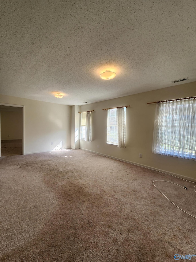 carpeted empty room with a textured ceiling