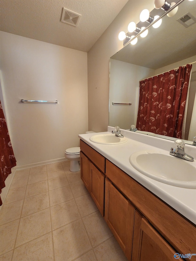 bathroom with tile patterned flooring, vanity, a textured ceiling, and toilet