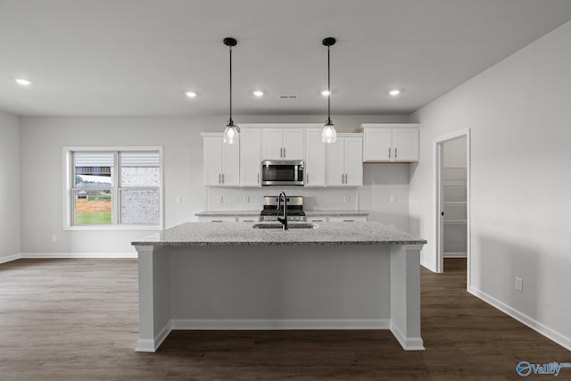 kitchen featuring light stone countertops, pendant lighting, stainless steel appliances, white cabinets, and sink